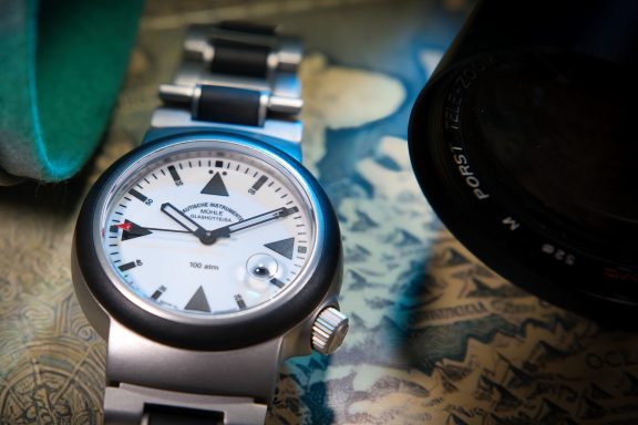 Ein modernes Armbanduhr mit silbernem Armband und schwarzem Ziffernblatt auf einem bunten Hintergrund.