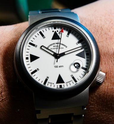 Armbanduhr mit schwarzem Zifferblatt, weißen Ziffern und einem roten Zeiger.